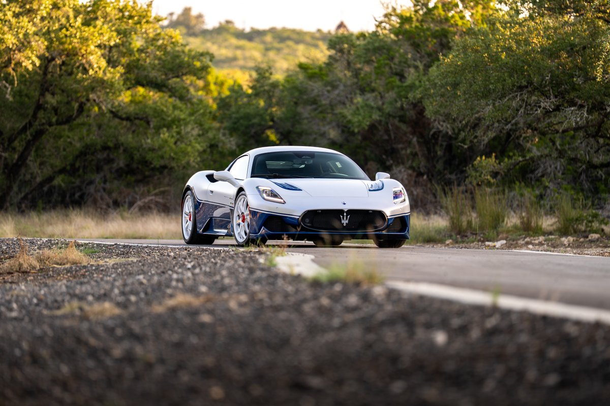 2024 Maserati MC20 Icona in white with blue trim and white rims driving on a road.