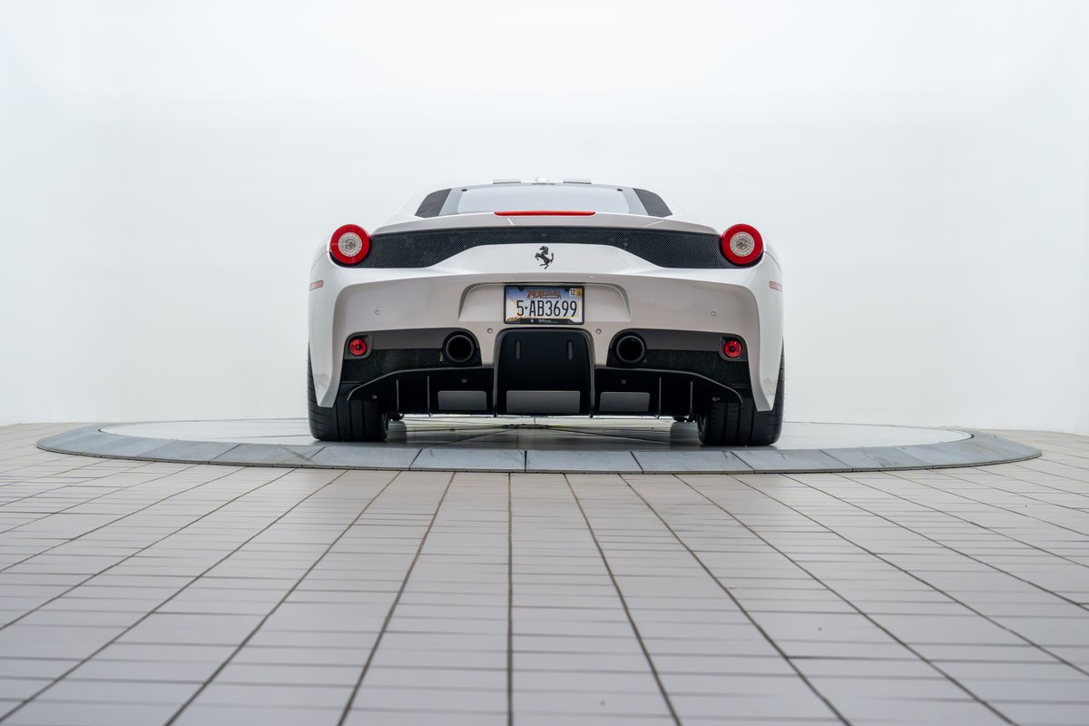 Rear view of a white 2015 Ferrari 458 Speciale, showcasing its quad exhaust, diffuser, and taillights.