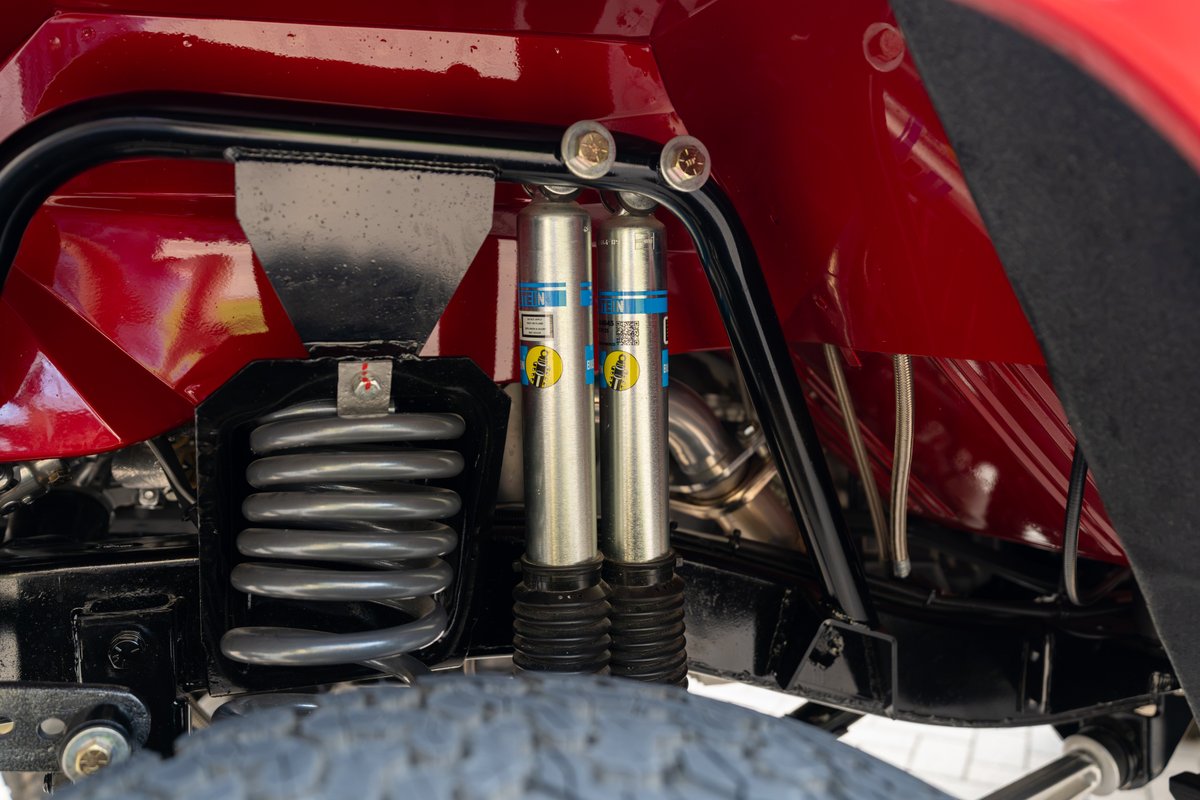 Red 1966 Ford Bronco rear suspension with Bilstein shocks and heavy-duty coil springs.