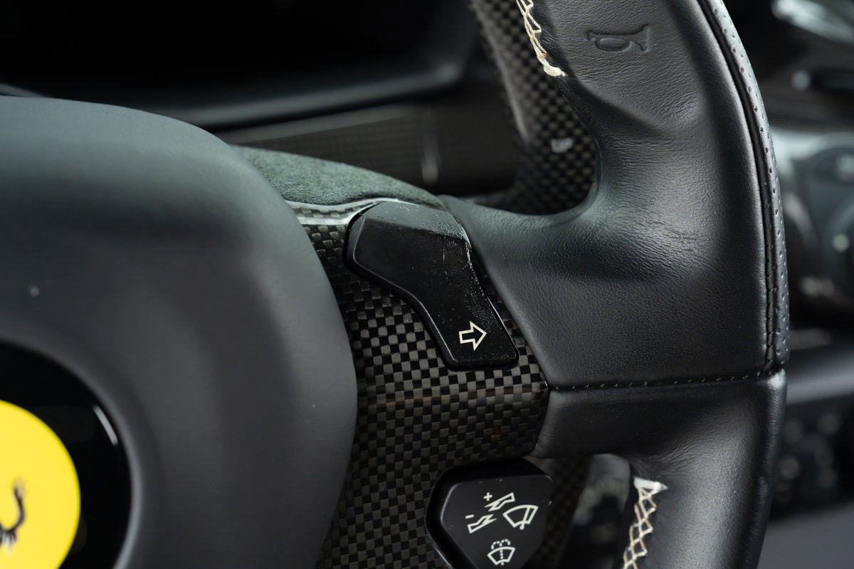 Close-up of a 2015 Ferrari 458 Speciale steering wheel with carbon fiber trim and paddle shifters.