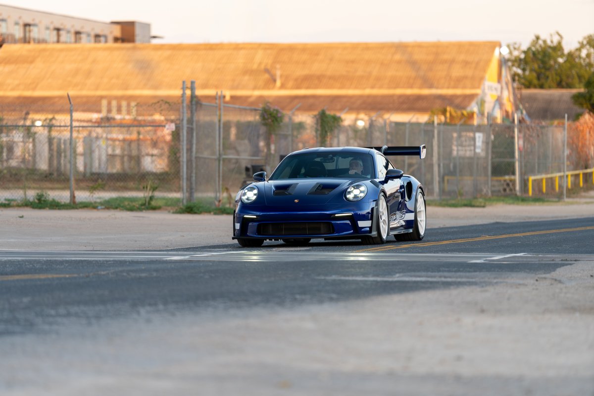 2025 Porsche 911 GT3 RS in blue with white rims and racing livery.