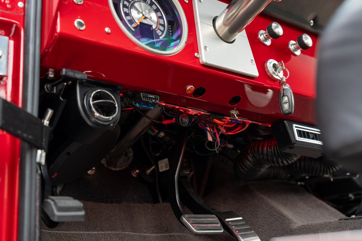 Red 1966 Ford Bronco interior with updated dash, gauges, and pedals.