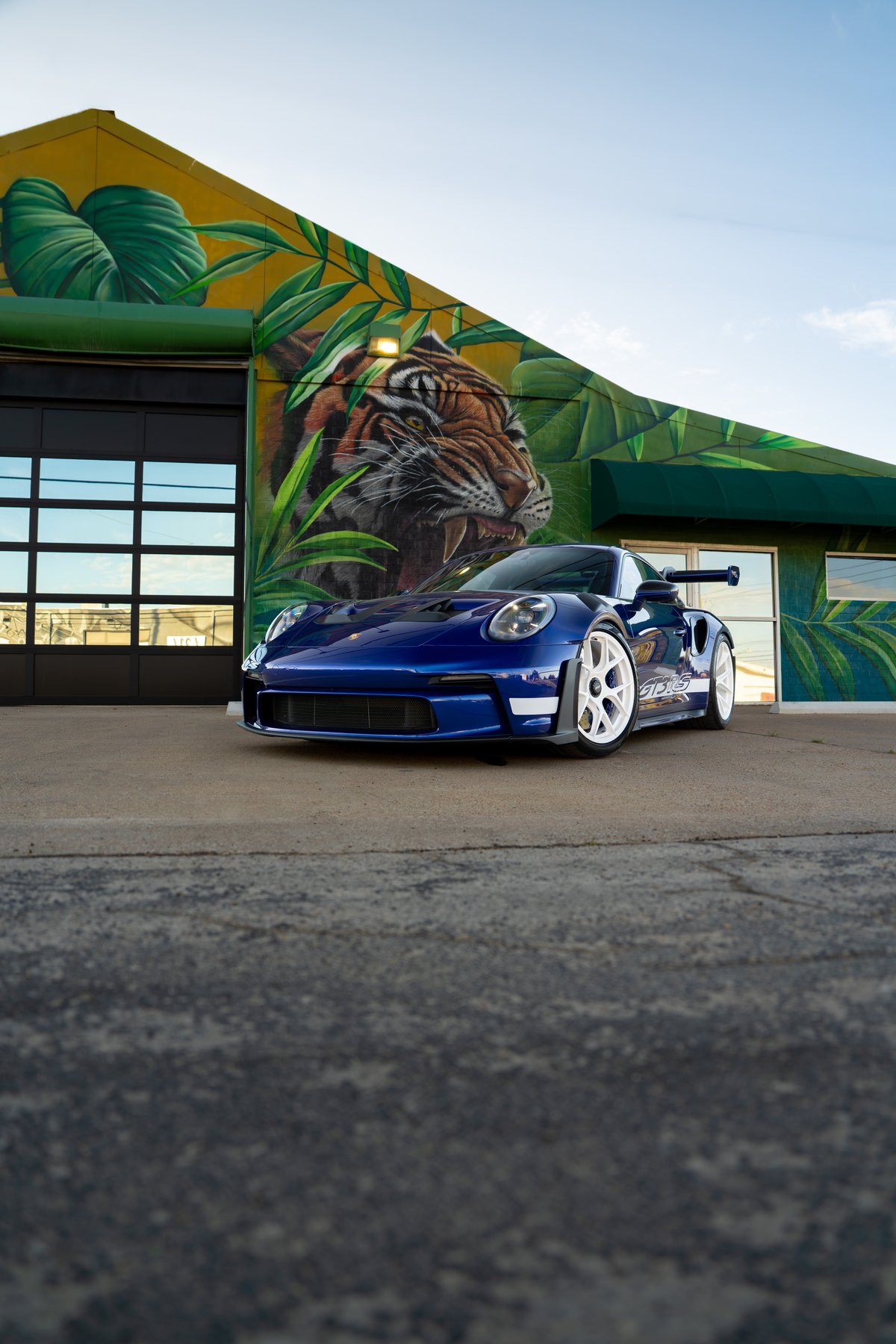 2025 Porsche 911 GT3 RS in blue with white rims and side stripe livery.