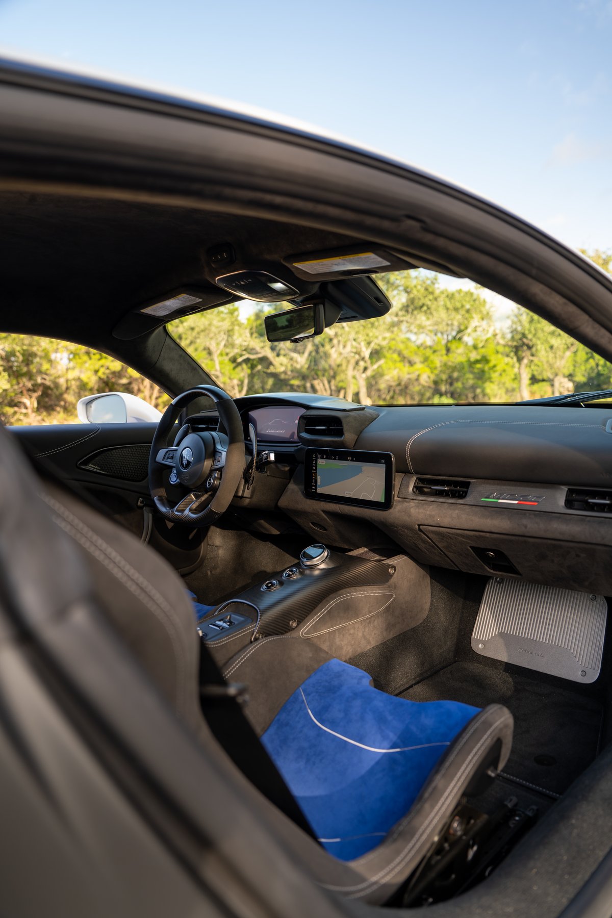 2024 Maserati MC20 Icona interior with carbon fiber trim, racing seats, and Italian flag livery accent.