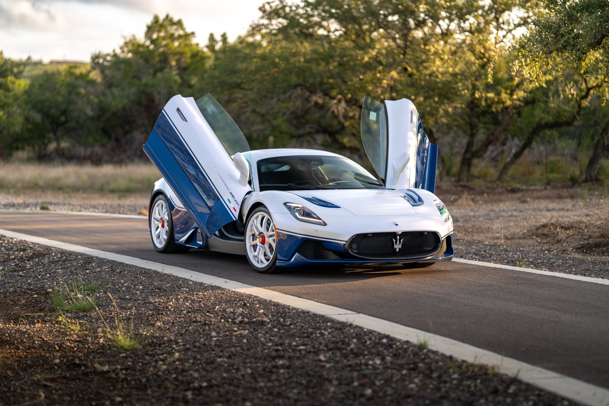 2024 Maserati MC20 Icona in white with blue trim and dihedral doors open, white rims with red accents.