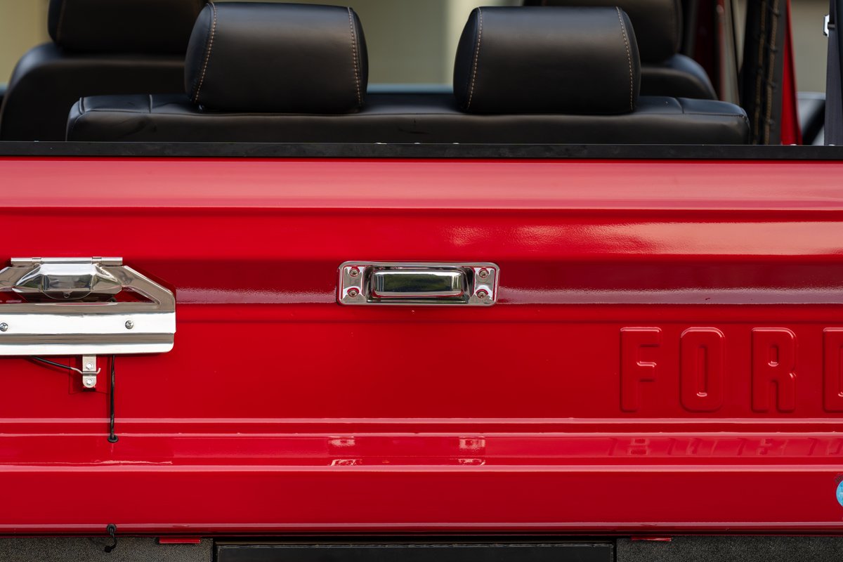 Red 1966 Ford Bronco rear with chrome handles and embossed "FORD" lettering.