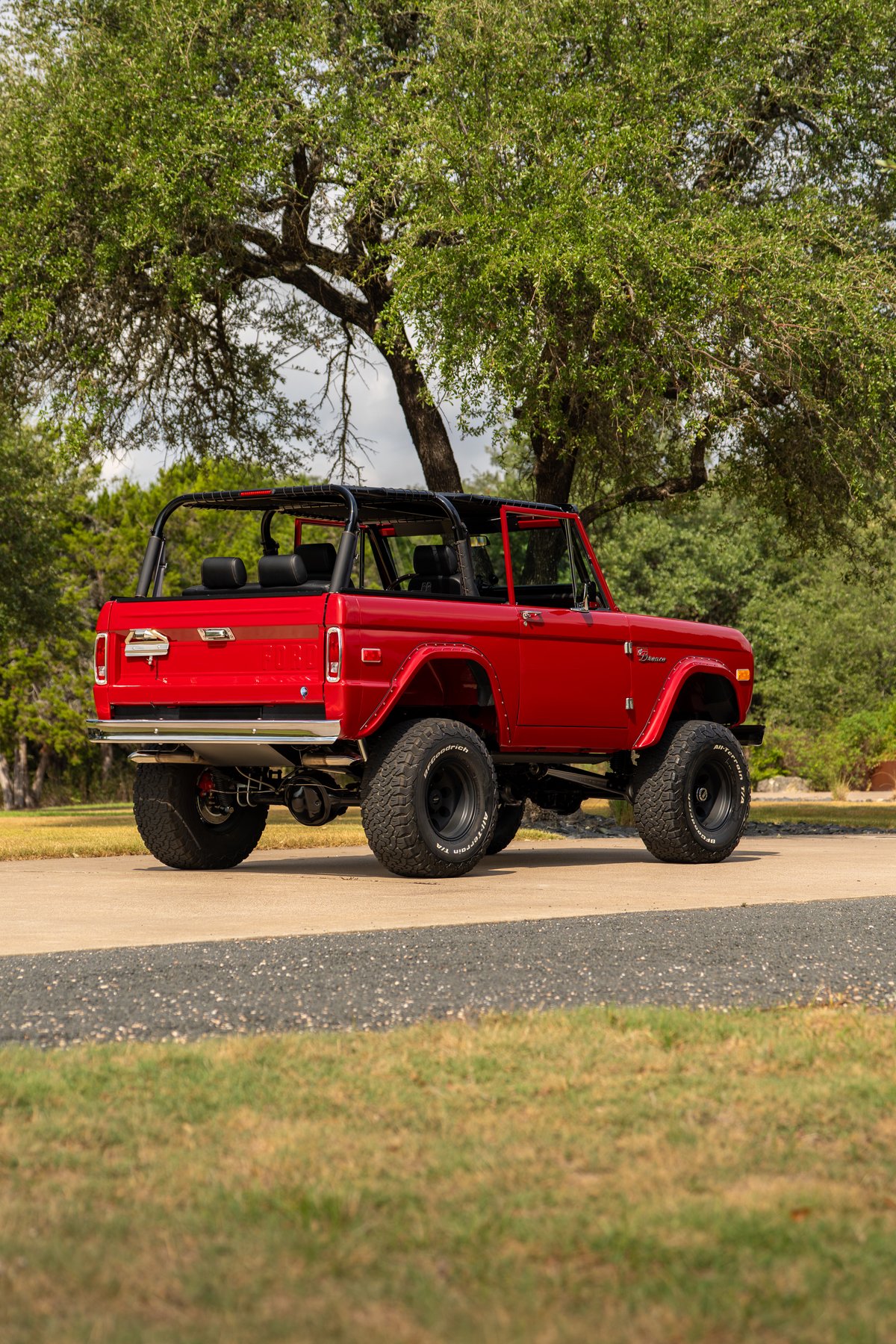 Red 1966 Ford Bronco by Atlas Broncos with black rims and off-road tires.