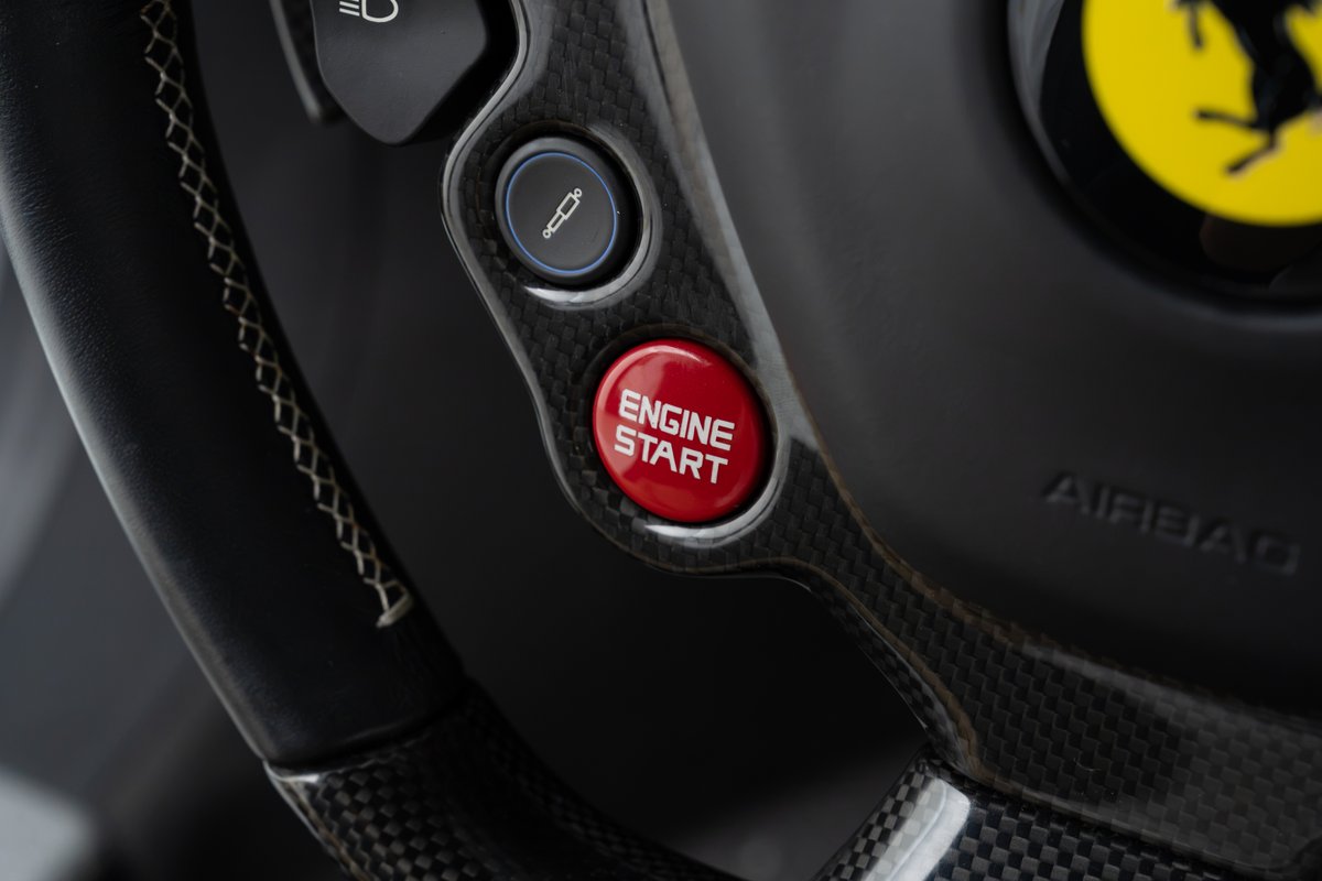 Red Ferrari 458 Speciale steering wheel with carbon fiber trim and engine start button.