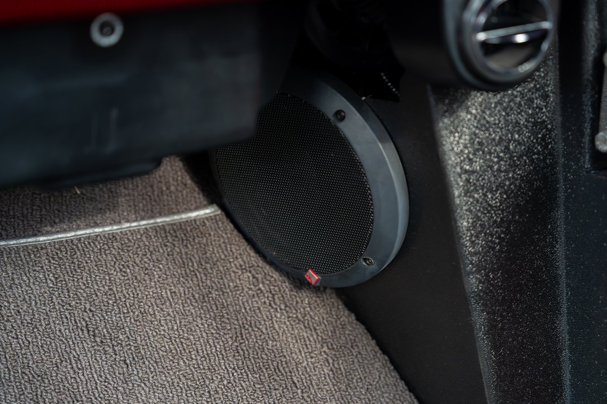 Close-up of a Rockford Fosgate subwoofer installed in the passenger footwell of a 1966 Ford Bronco by Atlas Broncos.