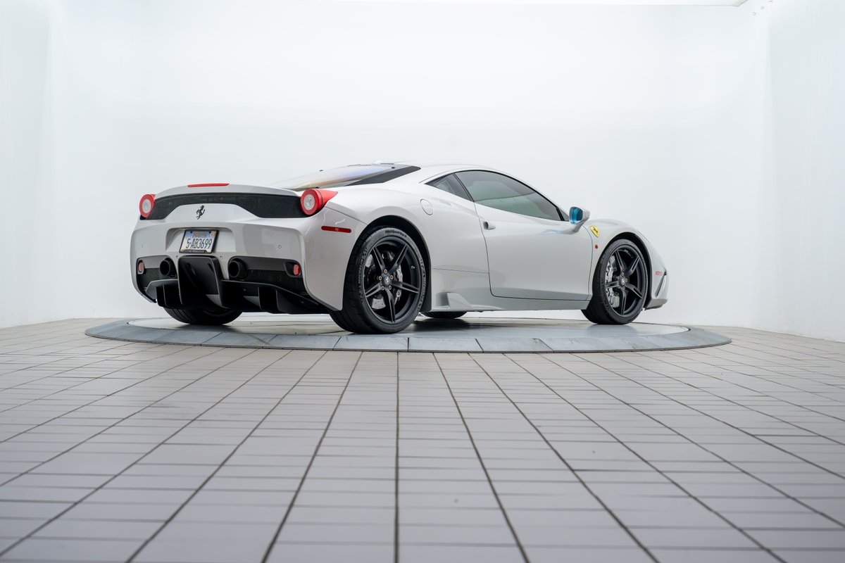 Rear view of a silver 2015 Ferrari 458 Speciale with black rims and quad exhaust tips.