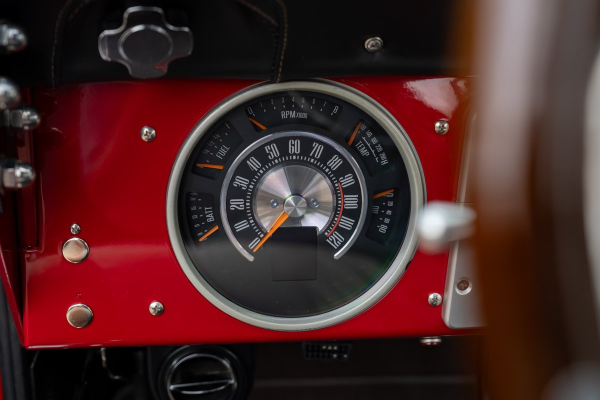Close-up of red 1966 Ford Bronco dashboard featuring a classic instrument cluster with analog gauges.