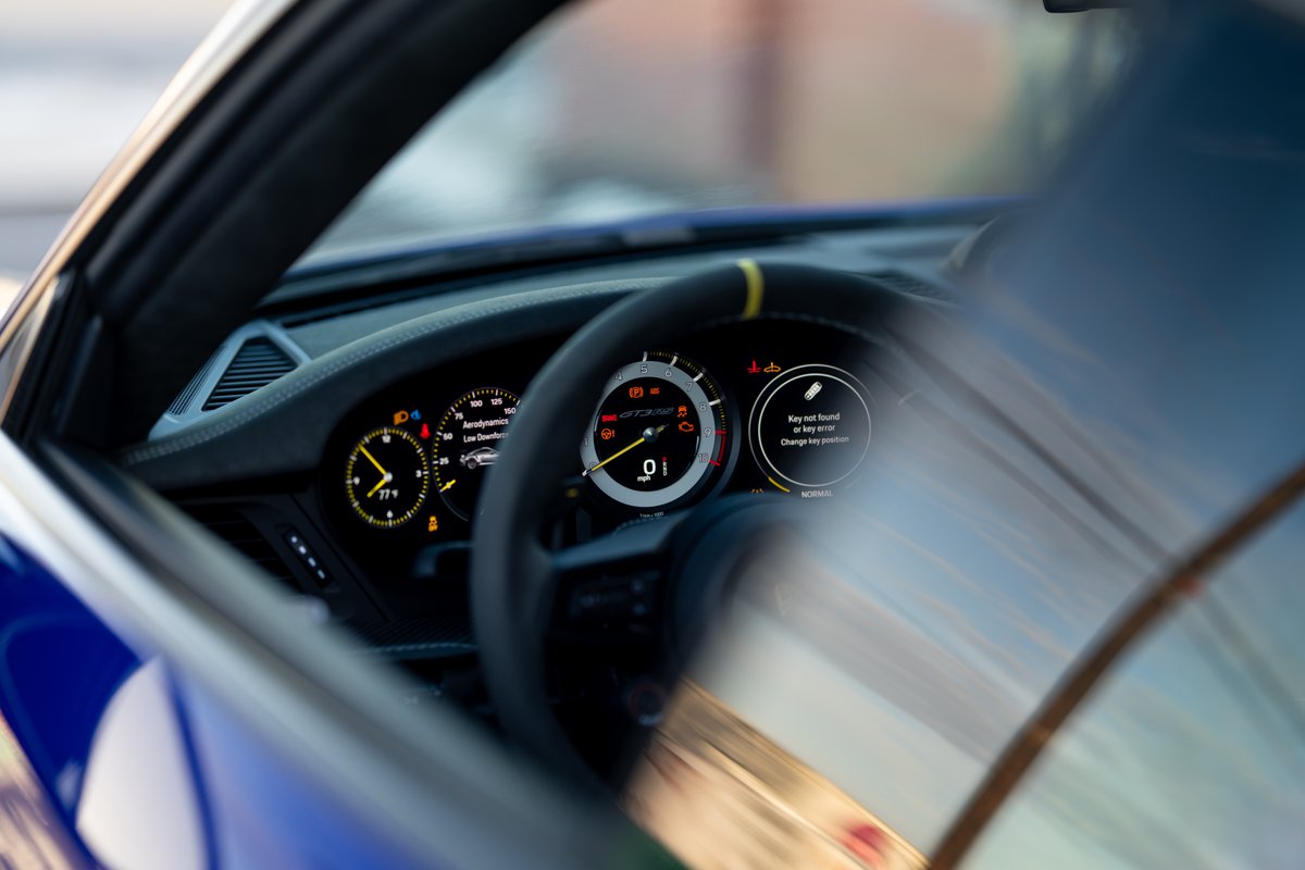 2025 Porsche 911 GT3 RS interior, blue exterior trim, digital dashboard displays speed.