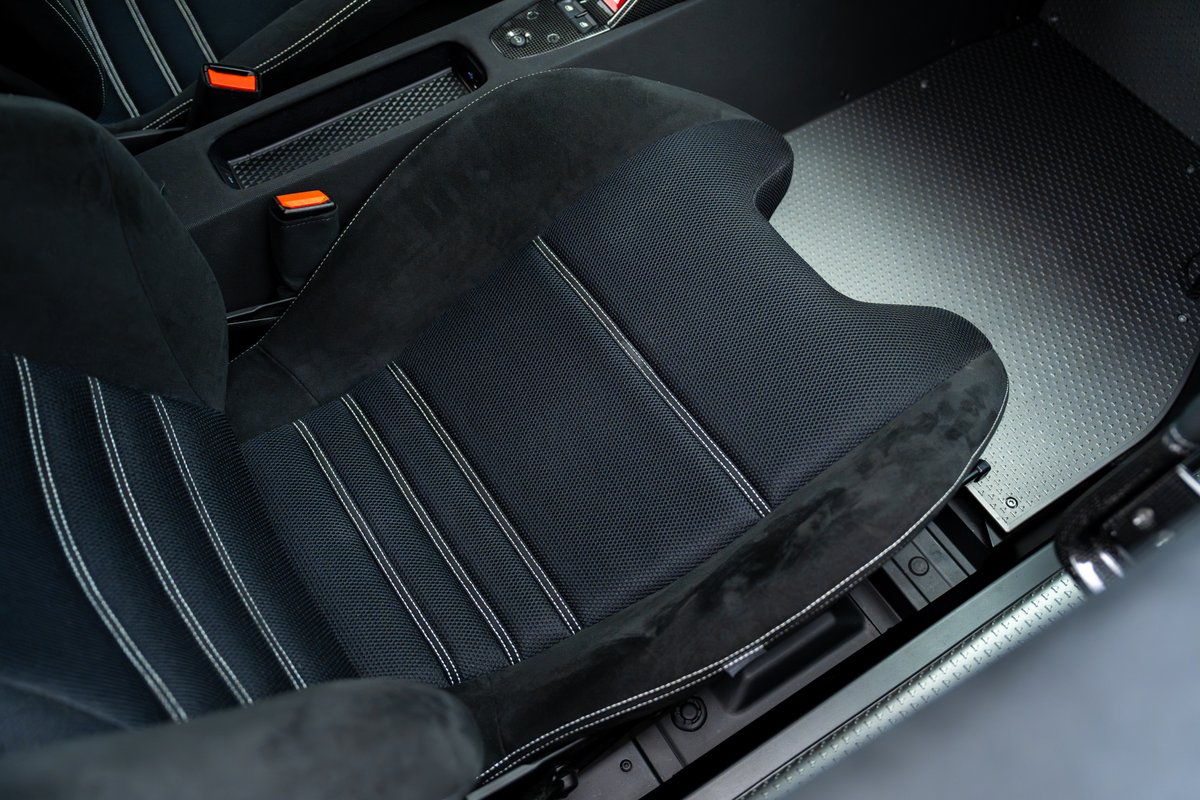 Close-up of the driver's seat in a 2015 Ferrari 458 Speciale, featuring black Alcantara and mesh upholstery with white contrast stitching.