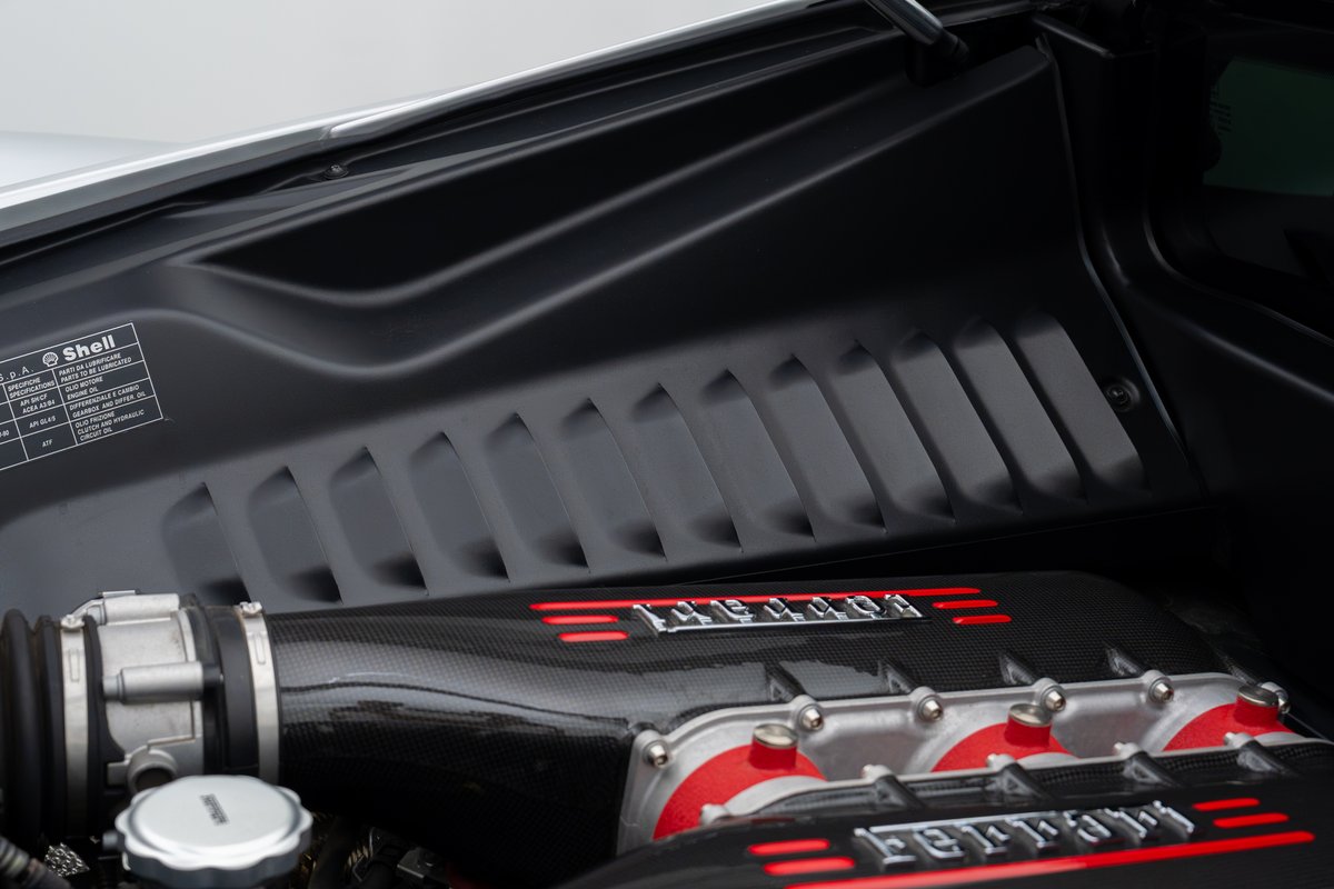 Ferrari 458 Speciale engine bay with carbon fiber intake manifold and red trim.