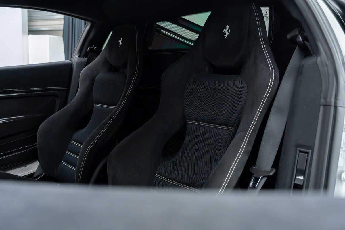 2015 Ferrari 458 Speciale interior, black suede sport seats with white stitching and Prancing Horse emblems.
