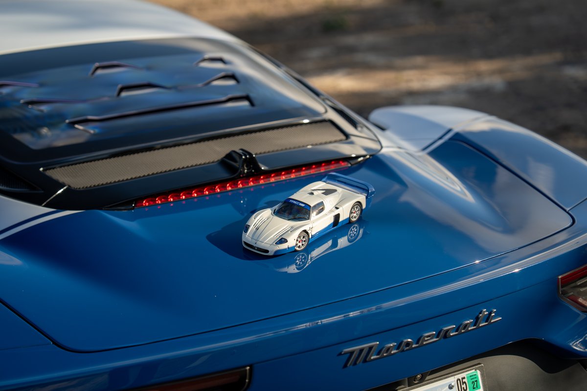 White and blue Maserati MC20 Icona with racing livery and model car.