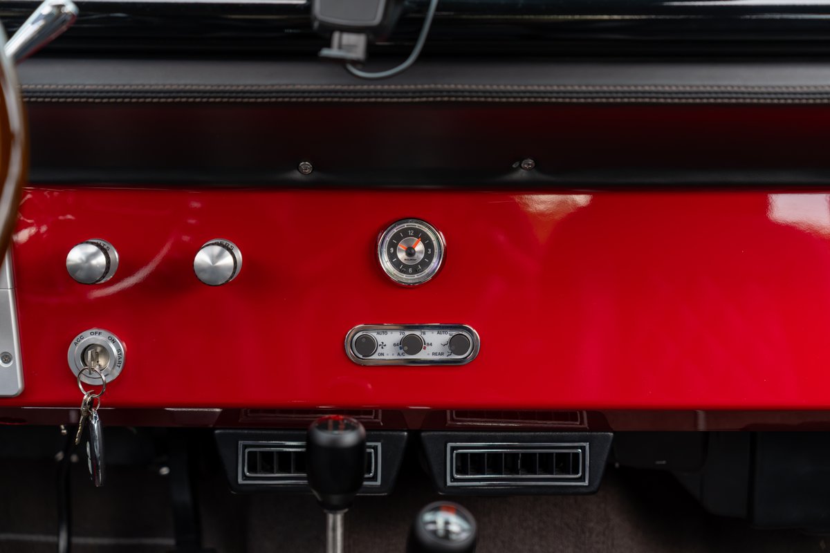 1966 Ford Bronco dashboard with red trim, vintage clock, and ignition key.