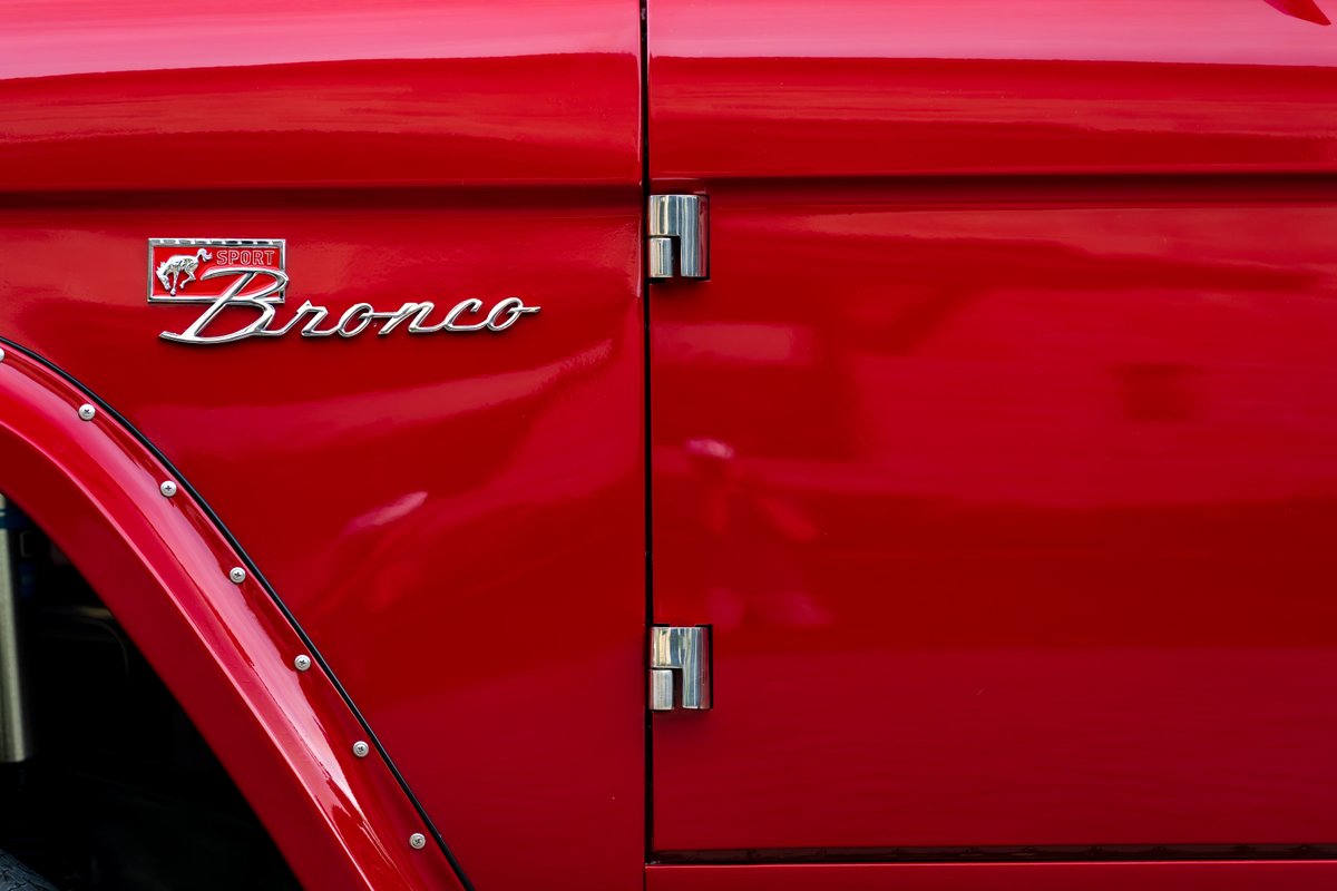 Red 1966 Ford Bronco Sport emblem with chrome trim and riveted fender flare.