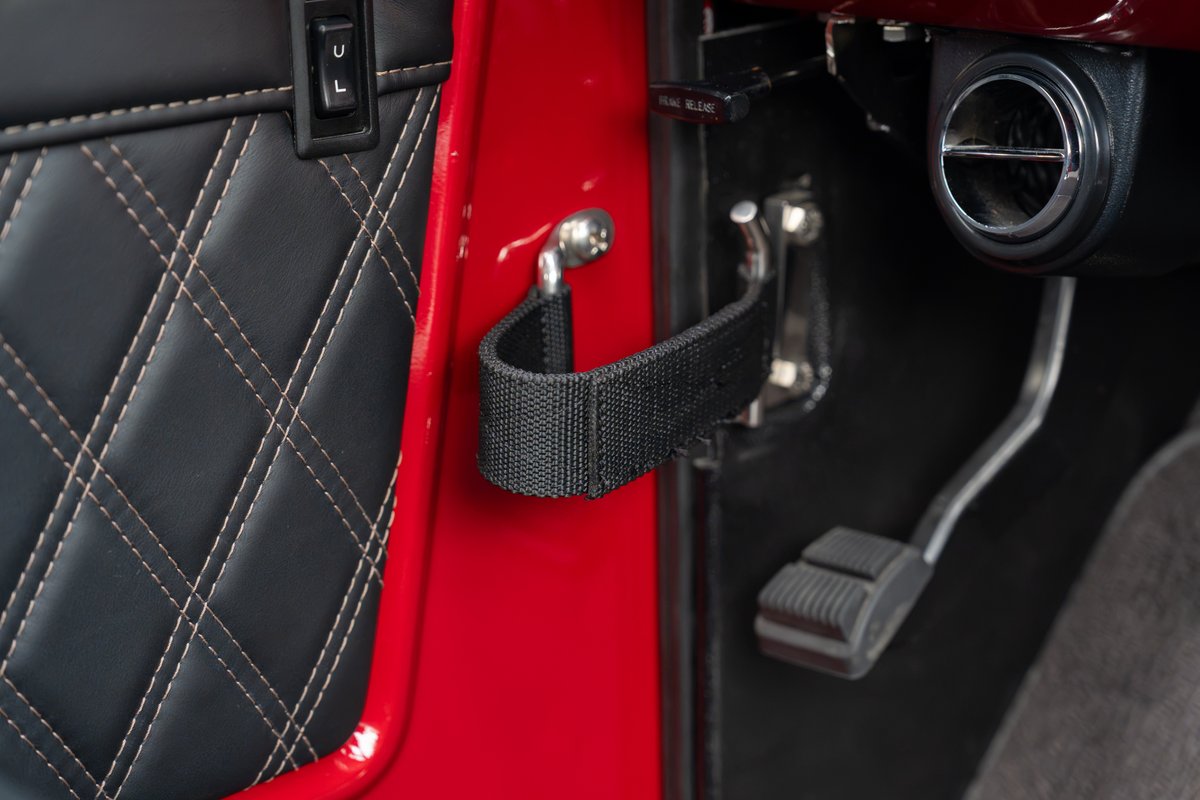 1966 Ford Bronco interior: red door panel with diamond stitching, strap pull, floor pedals & vent.