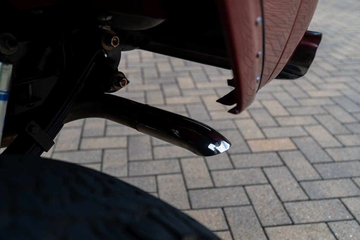 Close-up of a polished chrome exhaust tip on a maroon 1966 Ford Bronco by Atlas Broncos.
