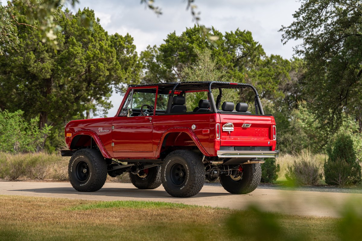 Red 1966 Ford Bronco by Atlas Broncos with black roll cage and off-road rims.