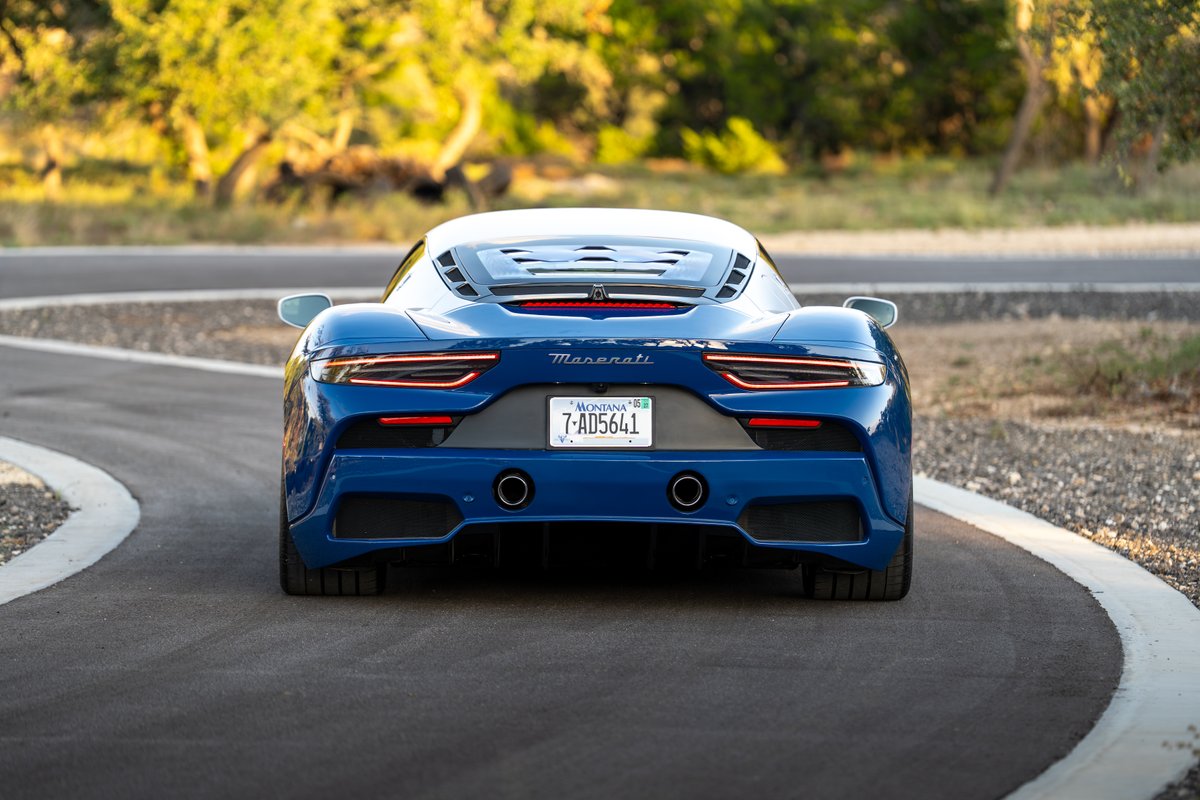Rear view of a blue 2024 Maserati MC20 Icona with quad exhaust tips and wide rear tires.