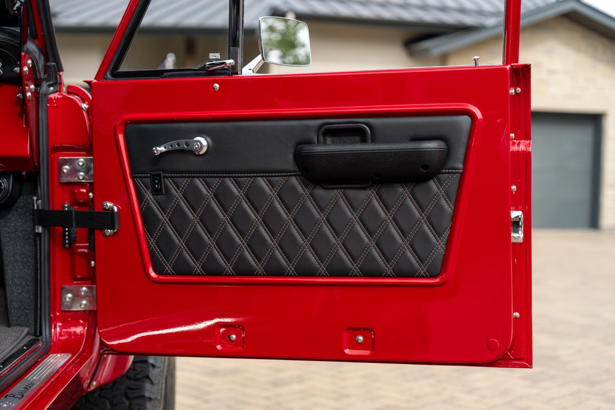 1966 Ford Bronco door interior with diamond-stitched black upholstery and red exterior trim.