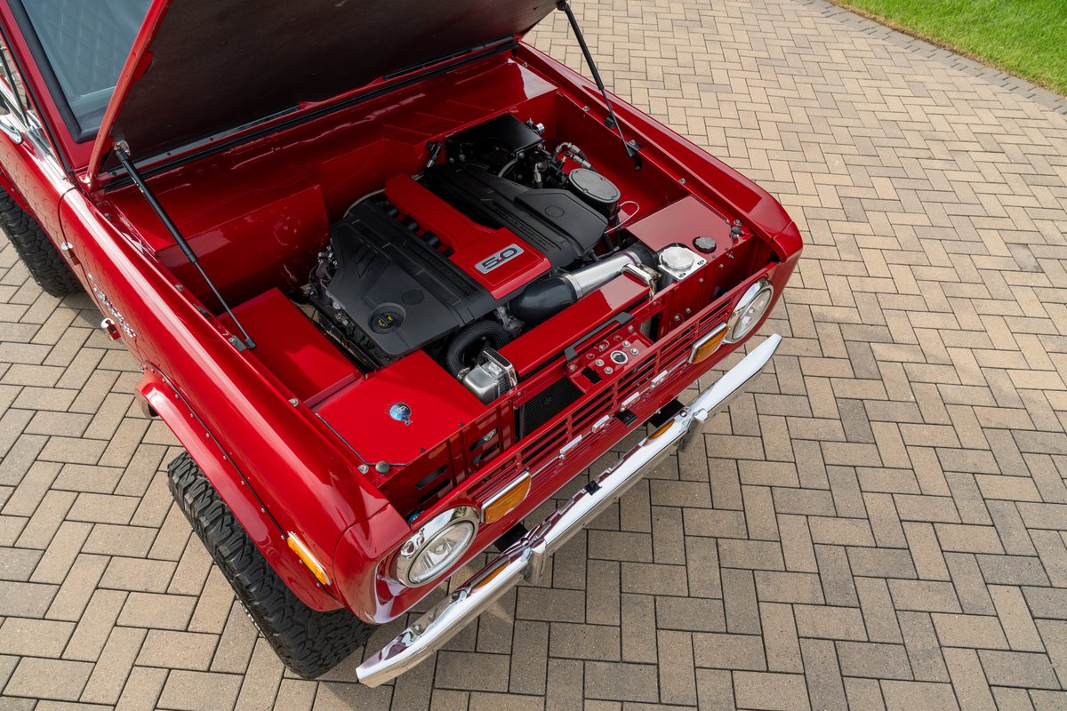 1966 Ford Bronco with Ford 5.0 Coyote V8 engine, red paint, and chrome bumper.