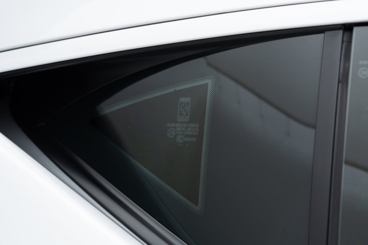 Close-up of the Ferrari emblem etched onto the rear quarter glass of a white 2015 Ferrari 458 Speciale.