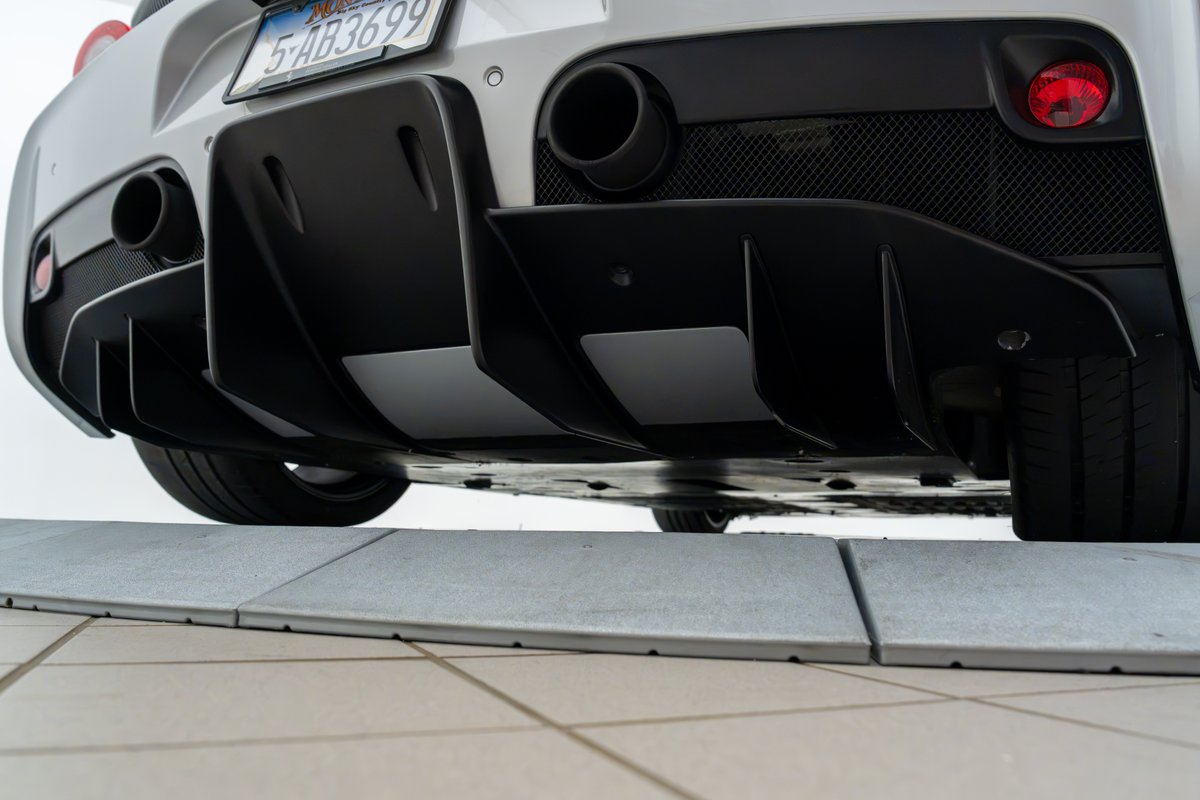 Rear view of a silver 2015 Ferrari 458 Speciale, showcasing its aggressive matte black diffuser.