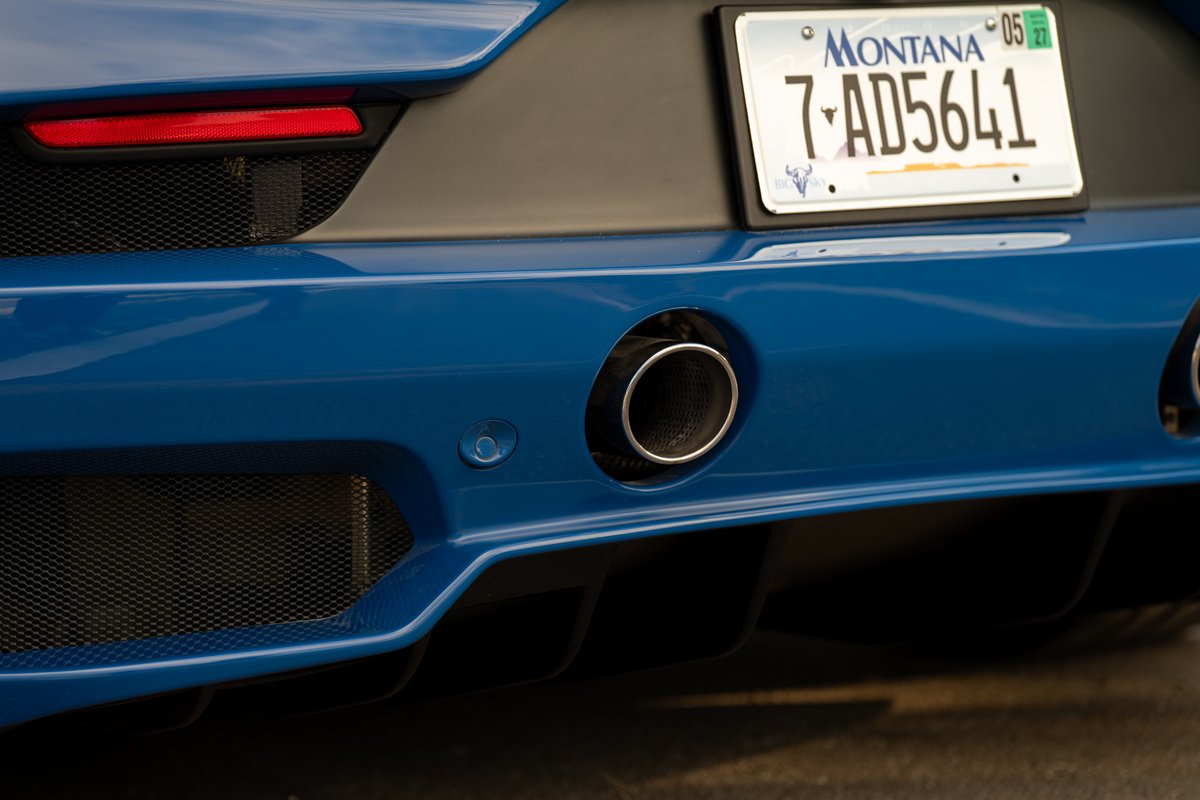 Rear view of a blue 2024 Maserati MC20 Icona, showing exhaust, bumper, and Montana license plate.