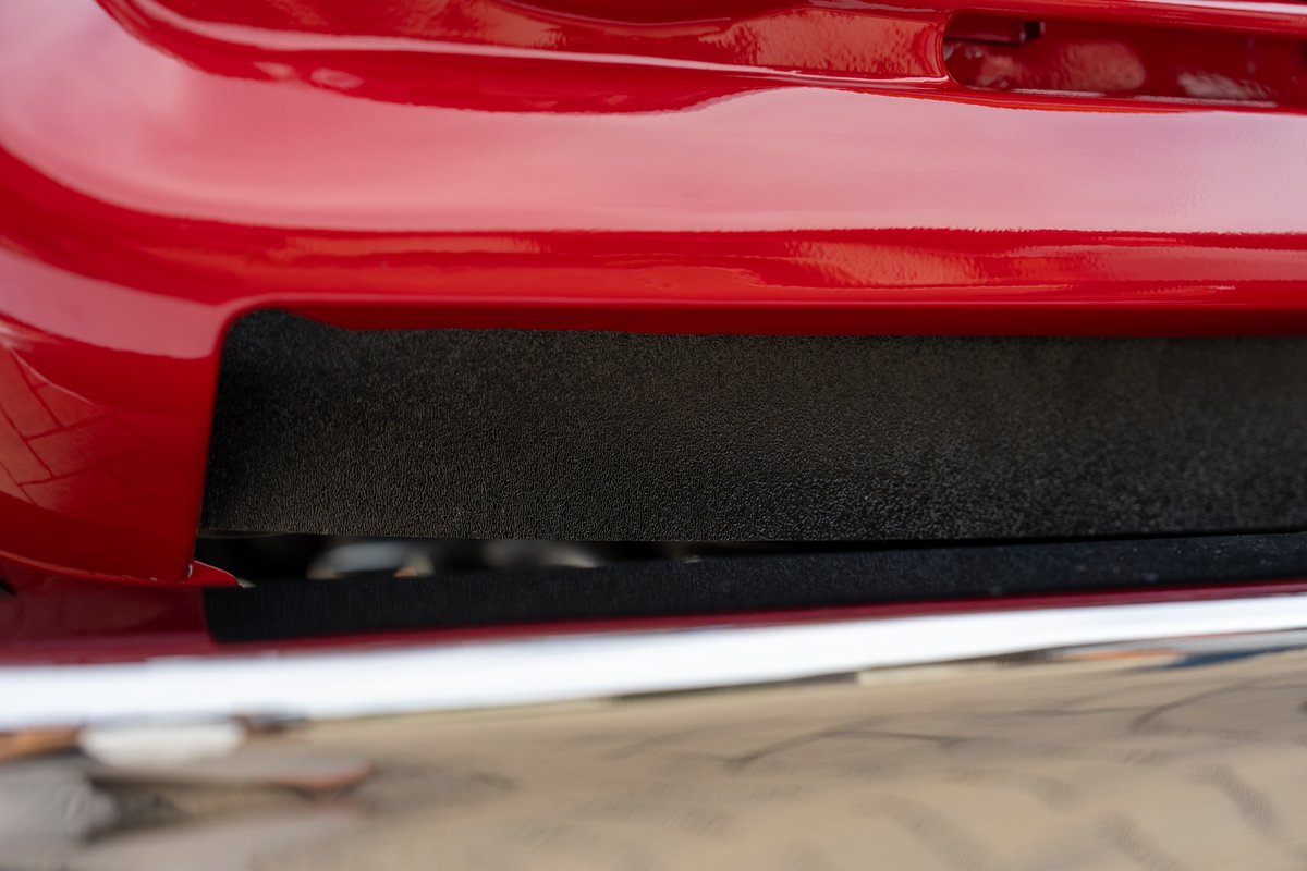 Close-up of a red 1966 Ford Bronco's body trim with a black textured insert.