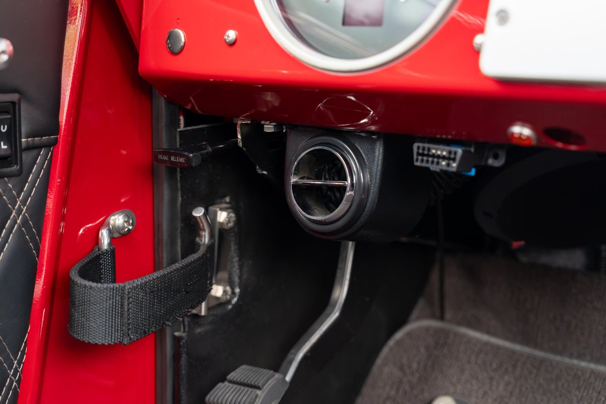 Red 1966 Ford Bronco interior showing a vent, fuel release, and strap.