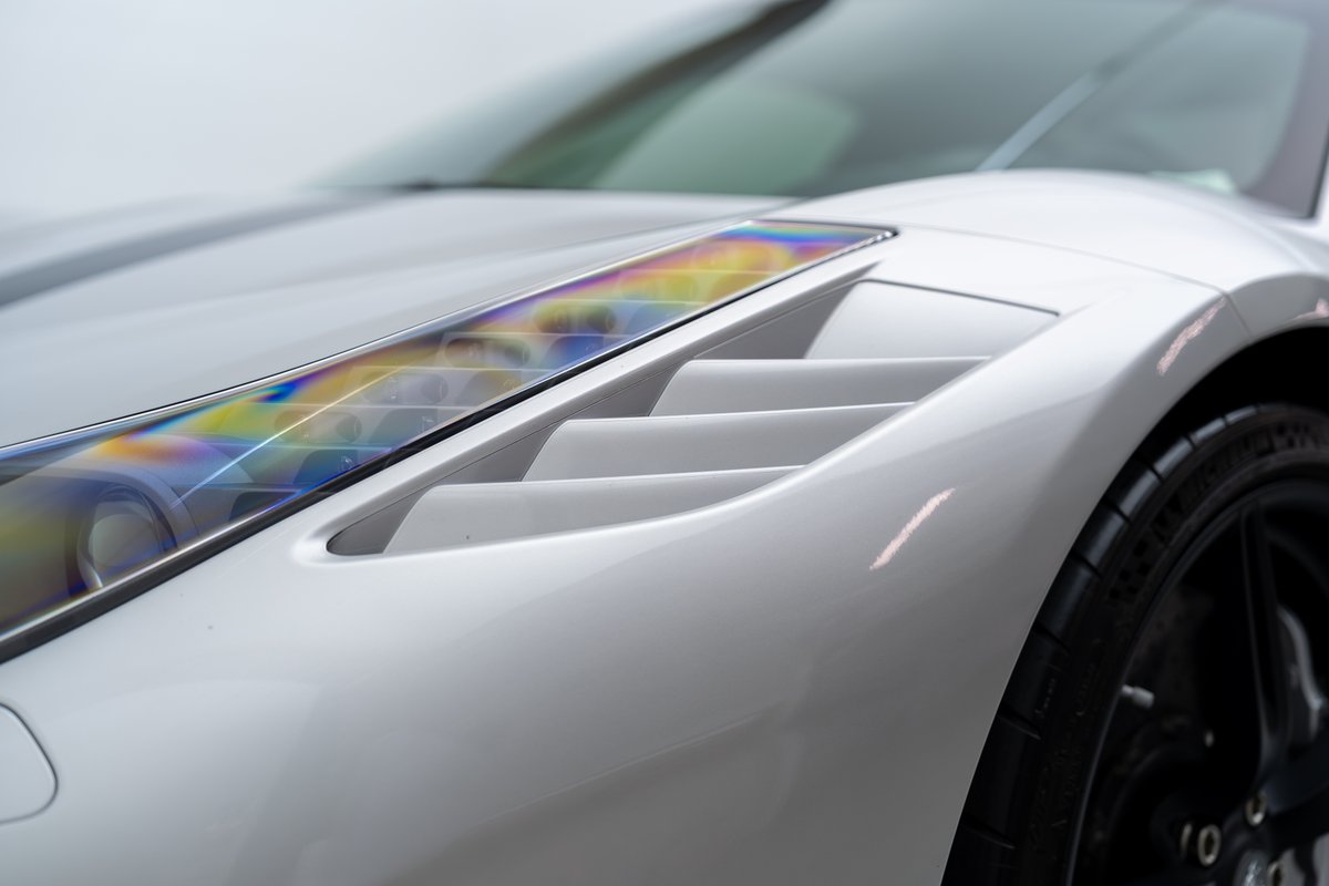 Close-up of a white 2015 Ferrari 458 Speciale's side vent and holographic headlight trim.