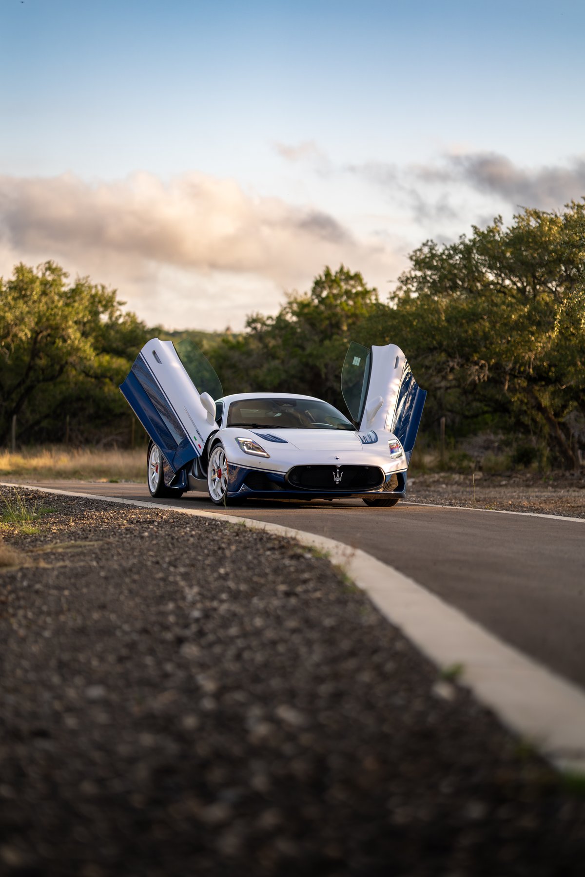 2024 Maserati MC20 Icona in white with blue livery, featuring butterfly doors open.