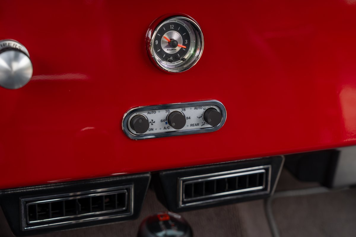 1966 Ford Bronco interior: red dash, vintage climate controls, chrome vent trim.