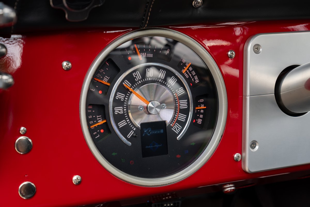 Close-up of a red 1966 Ford Bronco's custom gauge cluster with a digital display.