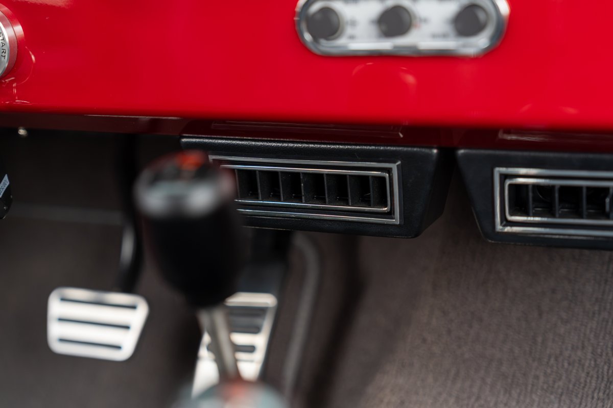 1966 Ford Bronco's chrome-trimmed AC vents, floor shifter, and pedals.