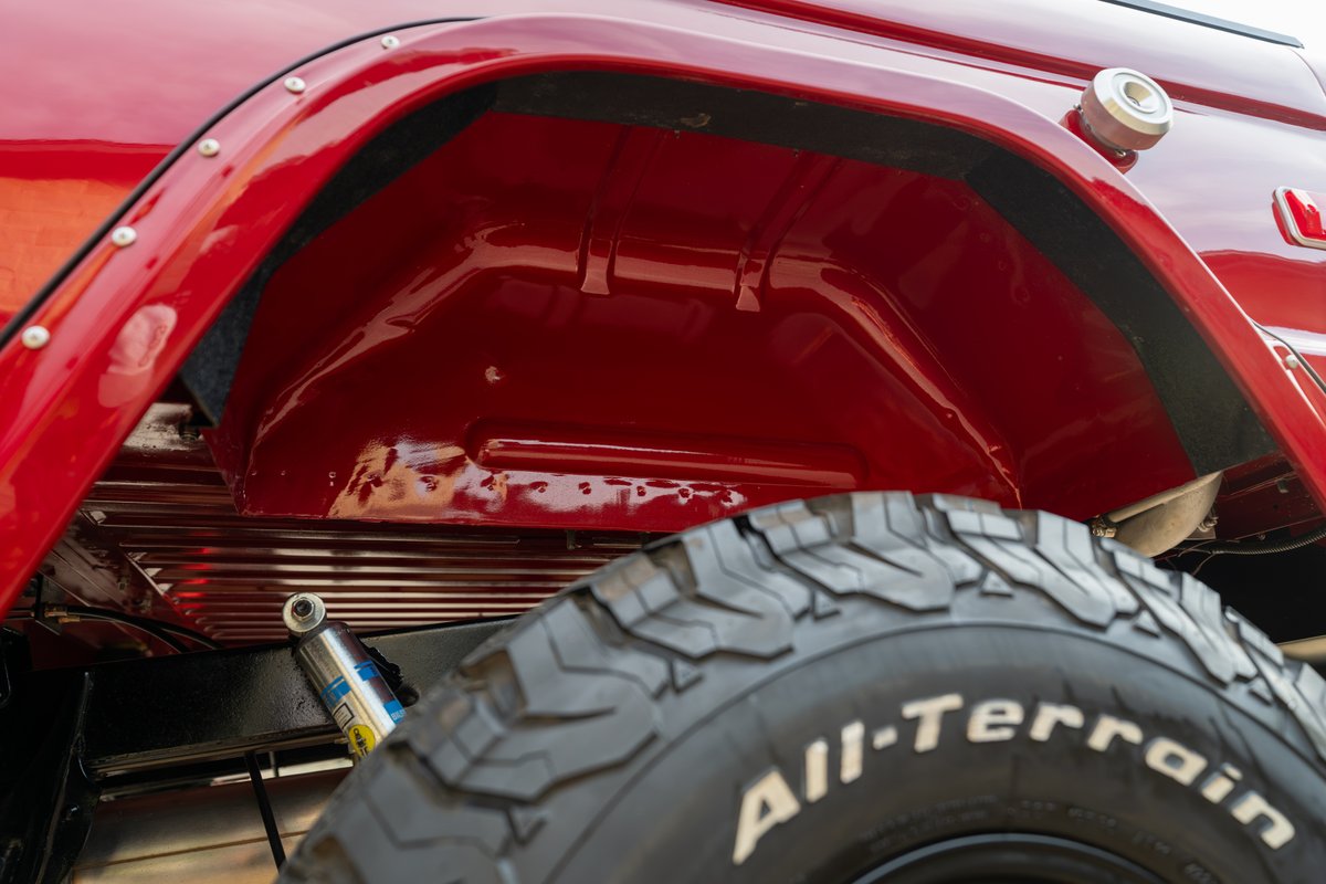 1966 Ford Bronco in red, with exposed wheel well, Bilstein shock, and All-Terrain tire.