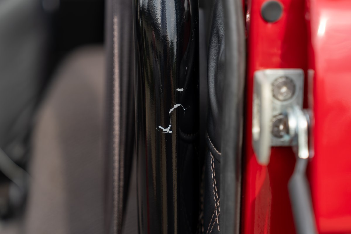 Close-up of a black roll bar with scuffs on a red 1966 Ford Bronco interior.