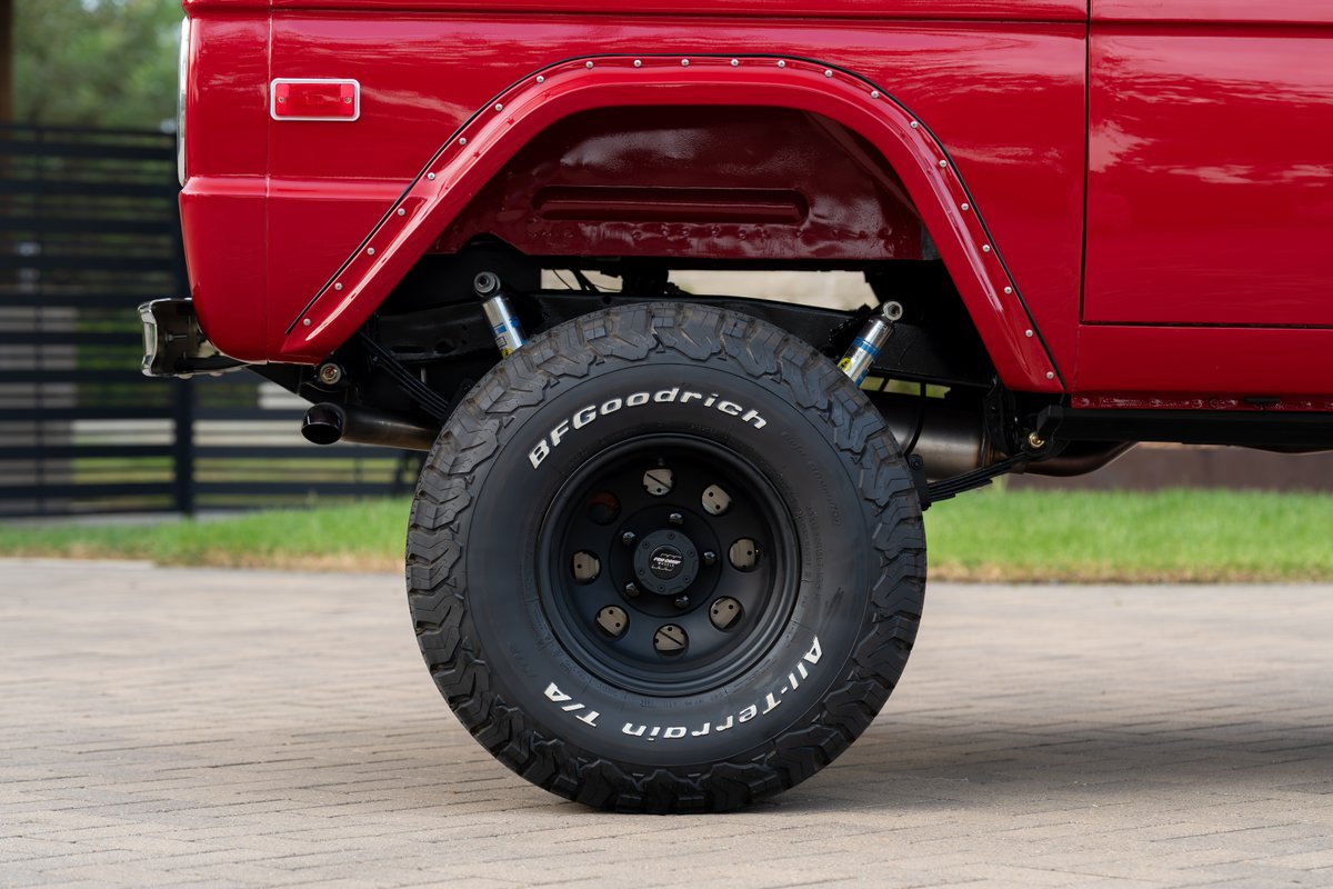 Red 1966 Ford Bronco with BFGoodrich All-Terrain T/A tires on black rims.