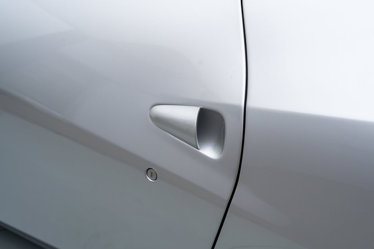 Close-up of a silver 2015 Ferrari 458 Speciale's flush door handle and lock cylinder.
