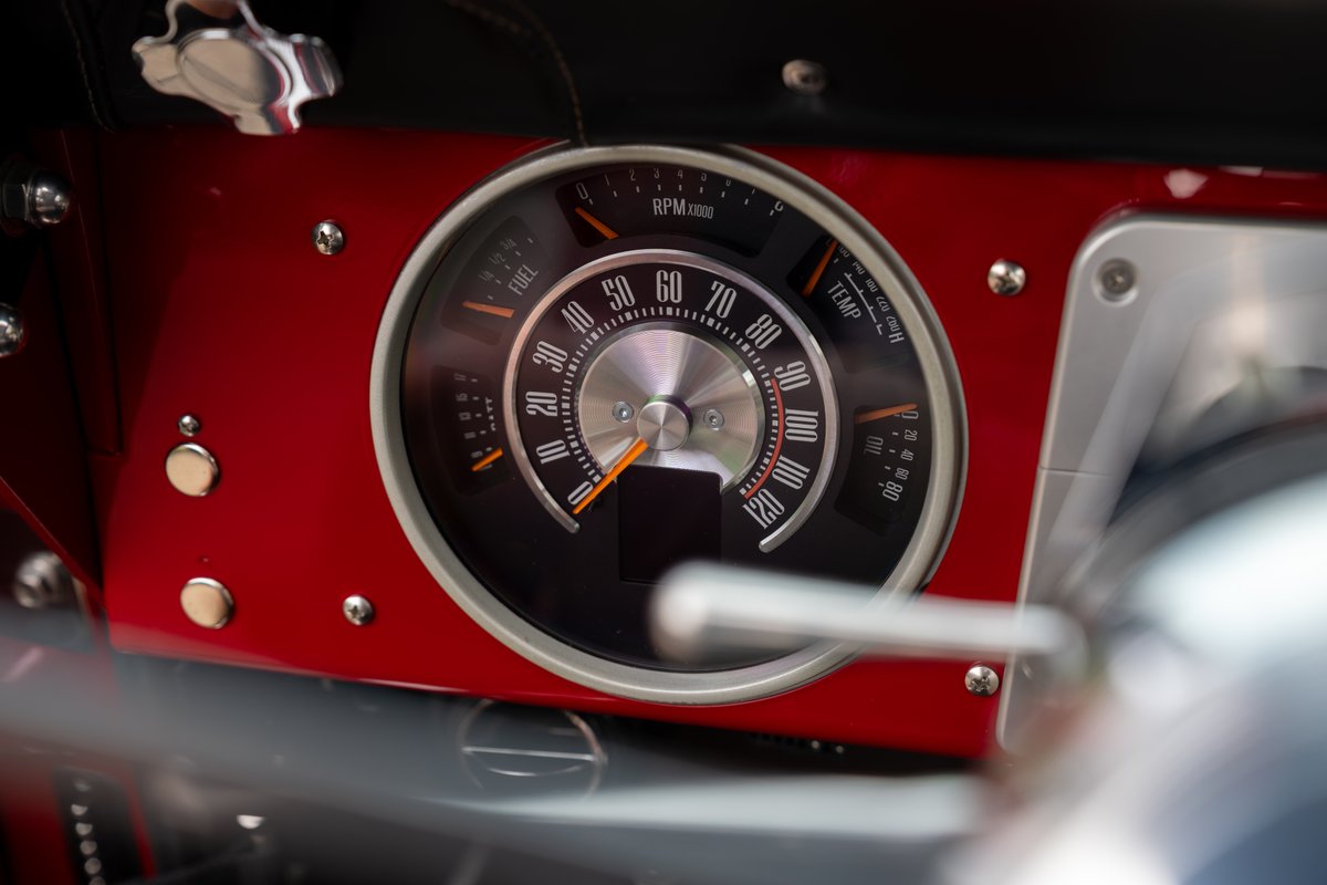 Classic 1966 Ford Bronco interior: Red dash trim, detailed gauge cluster with tachometer, fuel, temp, & oil gauges.