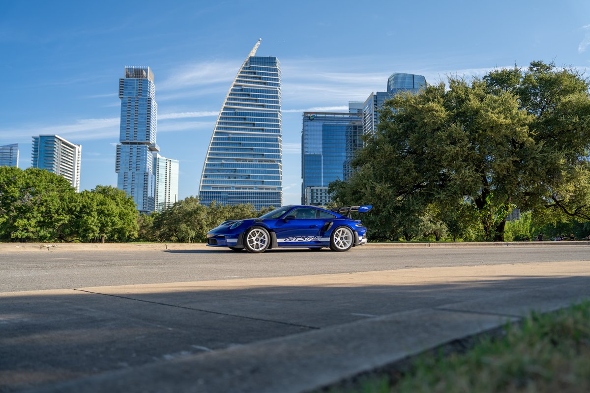 Blue 2025 Porsche 911 GT3 RS with white racing rims and side stripe livery.