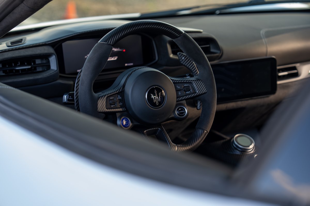 2024 Maserati MC20 Icona steering wheel with carbon fiber trim and digital display.