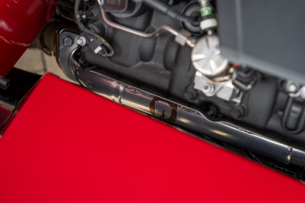 Close-up of a shiny exhaust pipe on a red 1966 Ford Bronco.