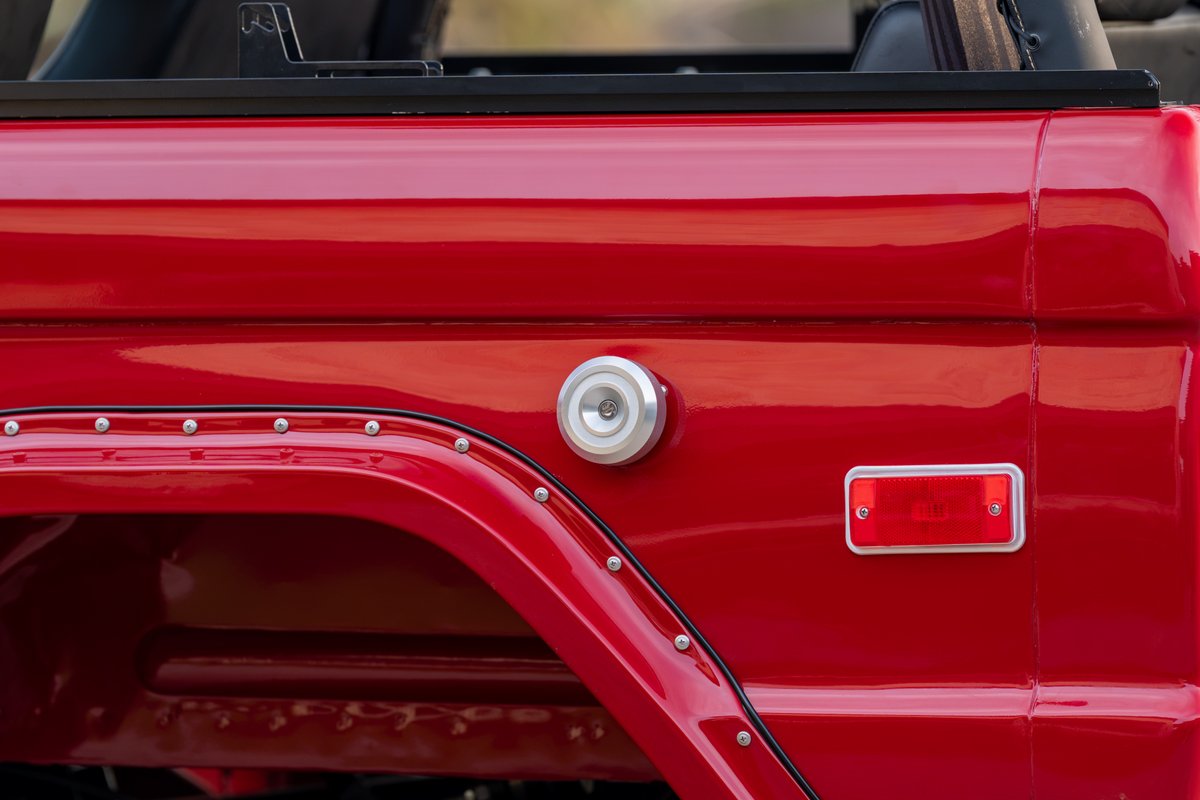 Close up of the red 1966 Ford Bronco's rear fender trim and fuel cap.