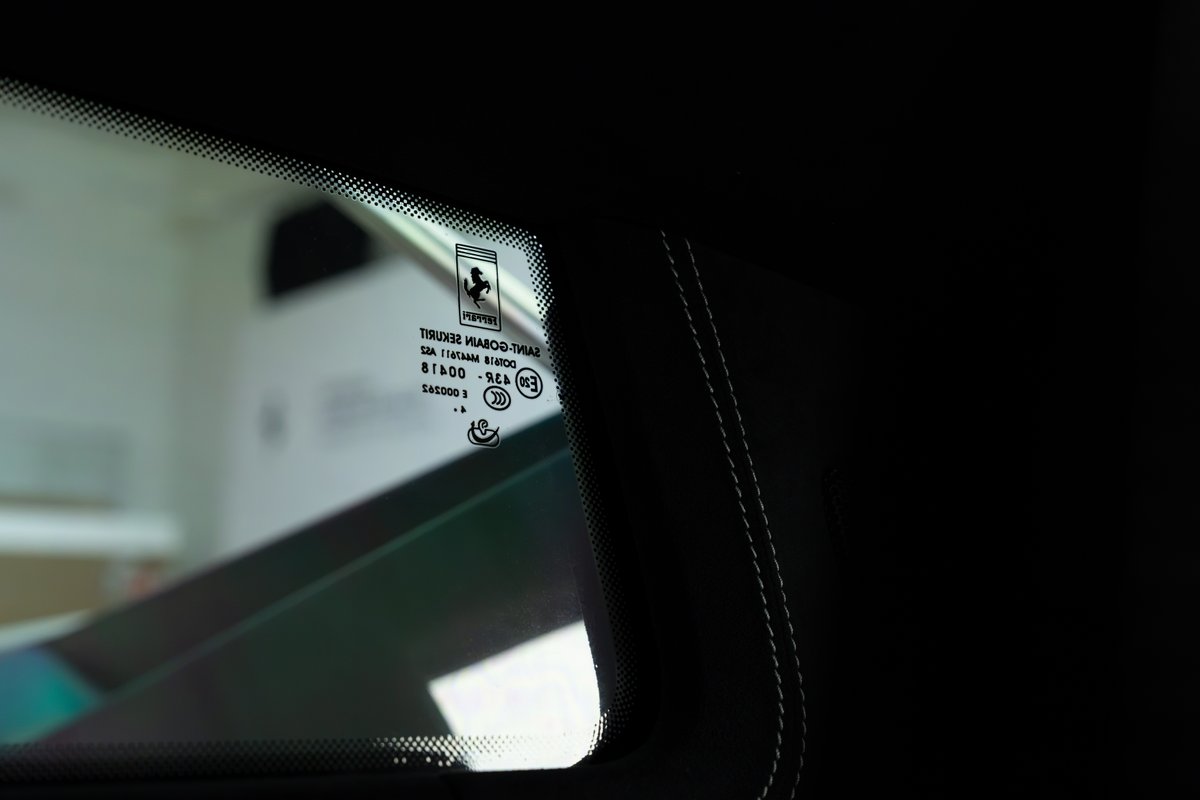 Close-up of a 2015 Ferrari 458 Speciale windshield with Ferrari logo and safety markings.