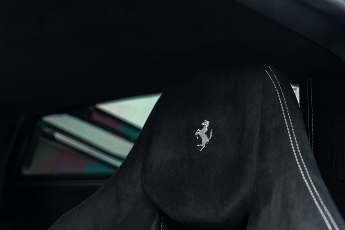 Black Ferrari 458 Speciale interior, with embossed Prancing Horse logo on headrest.