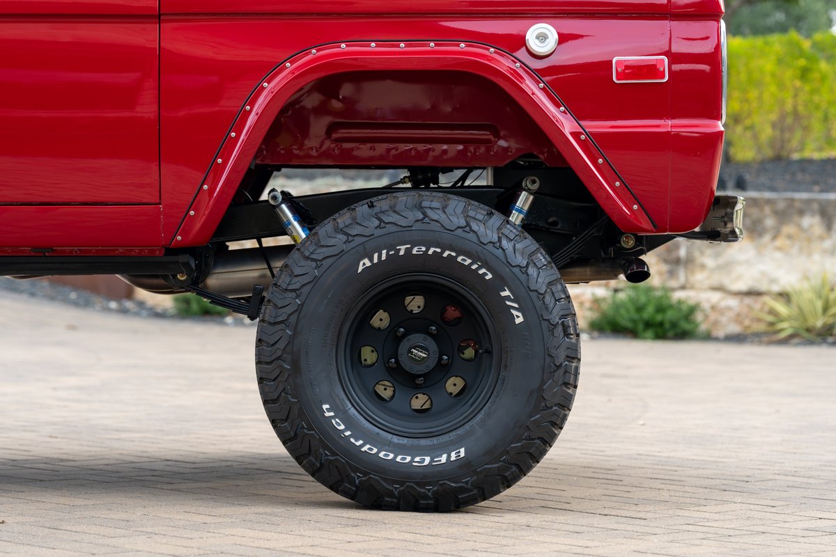 Red 1966 Ford Bronco rear wheel with BFGoodrich All-Terrain T/A tire and black rims.